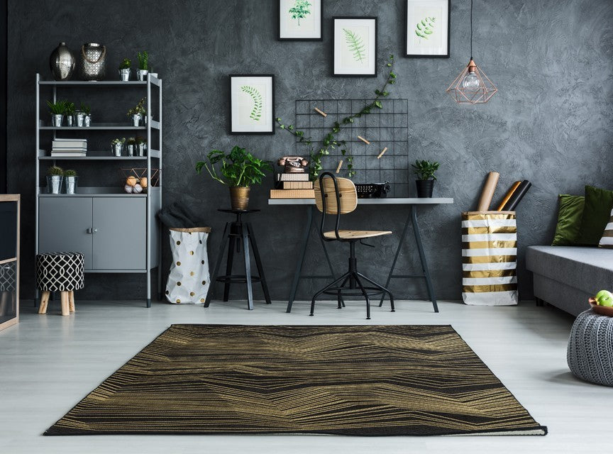 Alfombra 'Pulse' en una oficina moderna, con su patrón de chevron en dorado sobre un fondo oscuro. El diseño añade un toque de lujo y sofisticación al ambiente profesional. Ideal para aportar estilo contemporáneo a tu espacio de trabajo, y es lavable en lavadora para un mantenimiento sencillo.