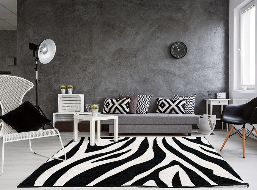 Alfombra 'Zebra' en un salón moderno y luminoso, mostrando cómo su patrón de rayas negras y blancas añade un toque gráfico y audaz al espacio.