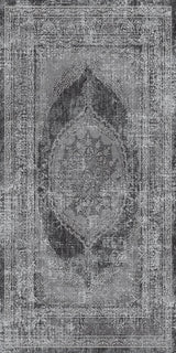 Alfombra 'Aria' mostrando su diseño texturizado en tonos de gris, negro y blanco, con un patrón central de medallón y bordes ornamentales que evocan estilos persas y turcos. El medallón oscuro contrasta con el fondo claro, dando un aspecto vintage. La alfombra es lavable en lavadora, con base antideslizante y sin pelusa.