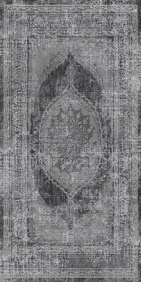 Alfombra 'Aria' mostrando su diseño texturizado en tonos de gris, negro y blanco, con un patrón central de medallón y bordes ornamentales que evocan estilos persas y turcos. El medallón oscuro contrasta con el fondo claro, dando un aspecto vintage. La alfombra es lavable en lavadora, con base antideslizante y sin pelusa.