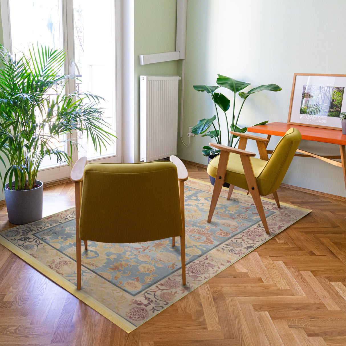 Alfombra 'Ariel' colocada en un salón moderno, resaltando su elegante diseño con patrones florales y ornamentales en una paleta de colores suaves. Los bordes detallados aportan un toque sofisticado al espacio, combinando lo clásico con lo moderno. La alfombra es lavable en lavadora, con base antideslizante y sin pelusa