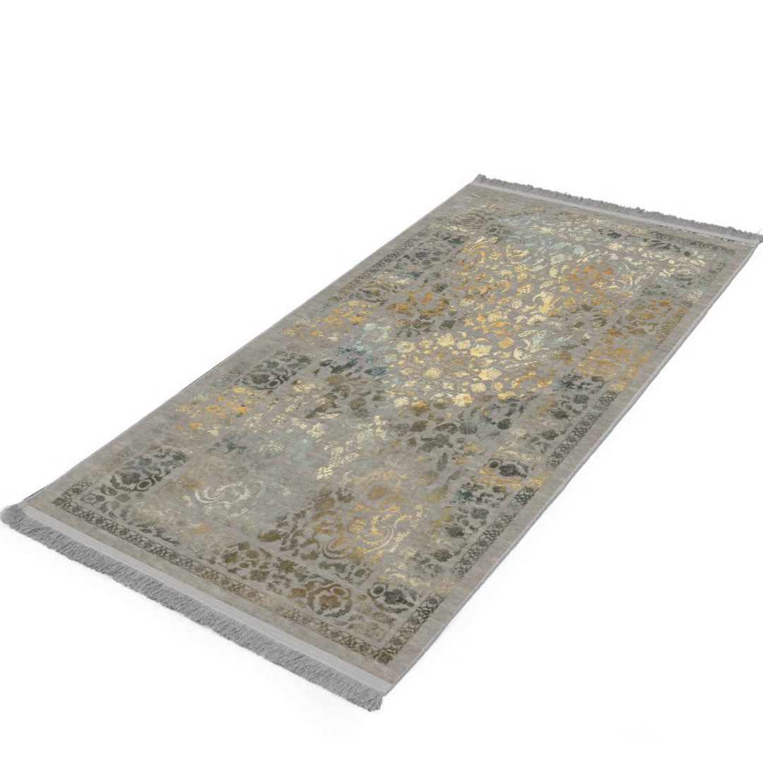 Alfombra 'Glimmer' sobre fondo blanco, resaltando su diseño elegante en tonos suaves y dorados con un patrón detallado que combina la tradición artesanal con el estilo contemporáneo. Ideal para añadir un ambiente cálido y con clase a cualquier decoración, prometiendo ser una adición duradera y memorable. Lavable en lavadora, base antideslizante, sin pelusas e hipoalergénica.