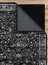 Alfombra 'Lustre' sobre un fondo blanco, resaltando su diseño simétrico con un medallón central y motivos geométricos en blanco, negro y gris, que aporta un toque de encanto vintage a cualquier espacio.