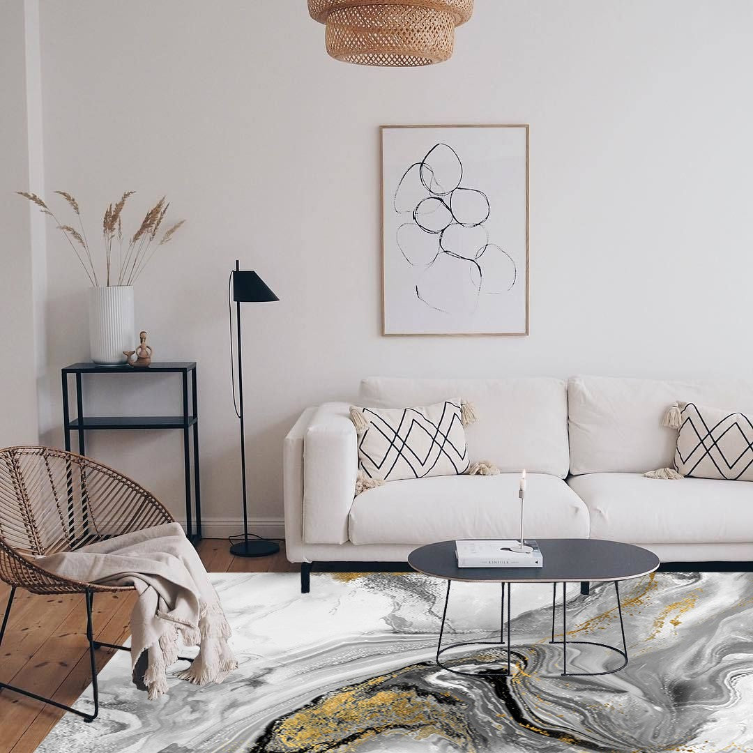 Alfombra 'Mármol' en una sala de estar moderna con muebles blancos. La alfombra presenta un diseño en tonos de gris y blanco con ondas fluidas y toques dorados, combinando elegancia y estilo en el ambiente