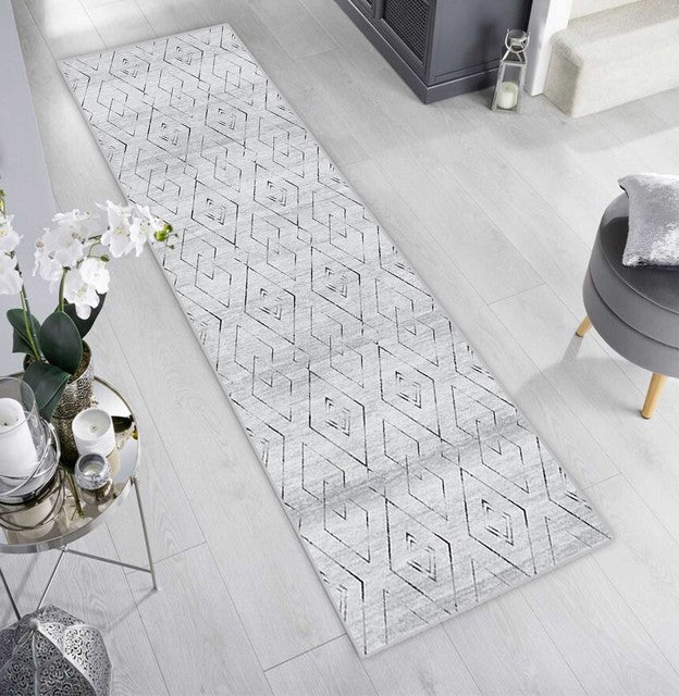 Alfombra 'Rhythm' en un salón moderno y luminoso, con su diseño geométrico de diamantes entrelazados que añade textura y sofisticación al espacio. Es ideal para complementar la decoración y es lavable en lavadora.