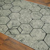 Esquina de la alfombra 'Terra', mostrando el patrón geométrico hexagonal en tonos grises que añade sofisticación y un toque moderno a la decoración.